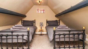 A room with two beds, a small table, and a picture on the wall. - G's Loft (Whitby)