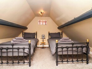 Ein Zimmer mit zwei Betten, einem kleinen Tisch und einem Bild an der Wand.