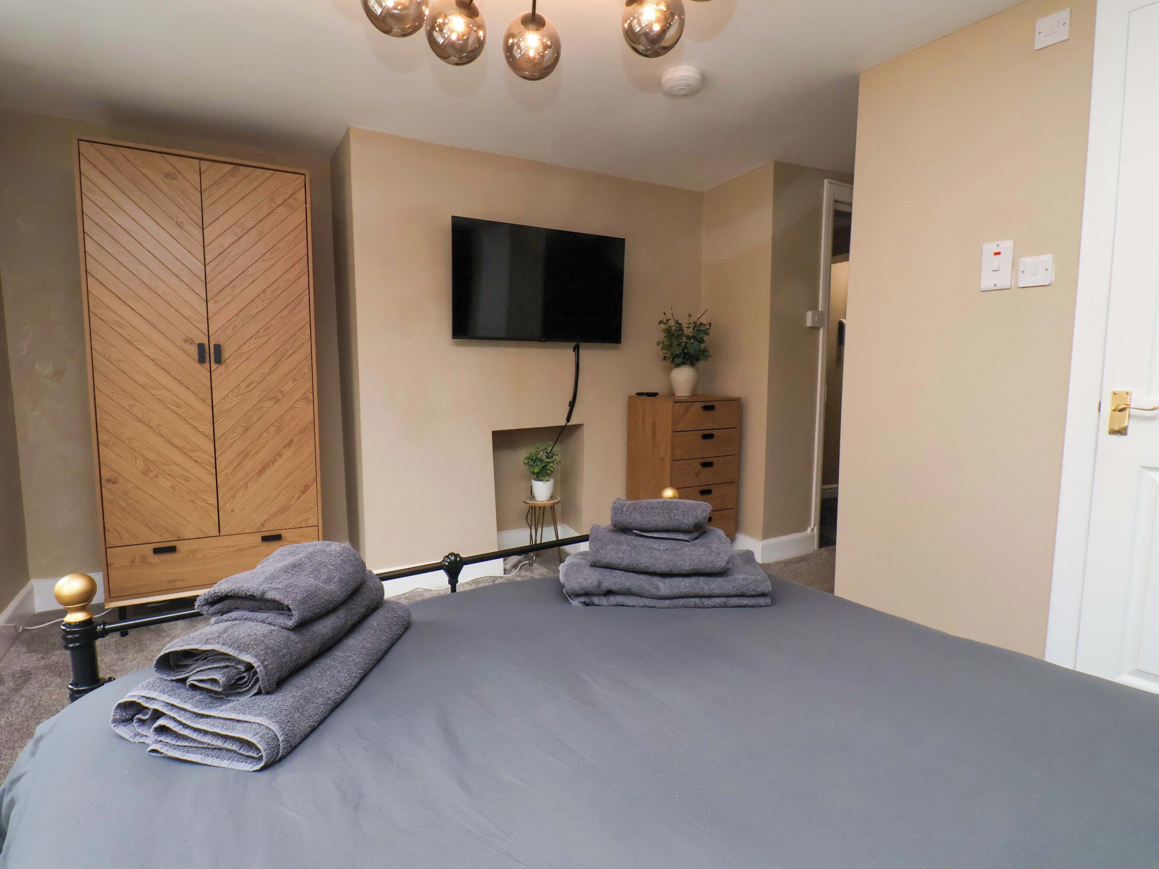 A bedroom with a bed, a wardrobe, a television, and a small plant.