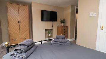 A bedroom with a bed, a wardrobe, a television, and a small plant.