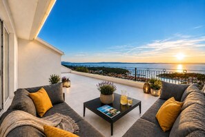 Ein Balkon mit einer Couch, einem Couchtisch und Topfpflanzen.