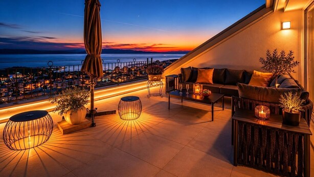 Eine Dachterrasse mit einer Couch, Sesseln, einem Tisch und Topfpflanzen.