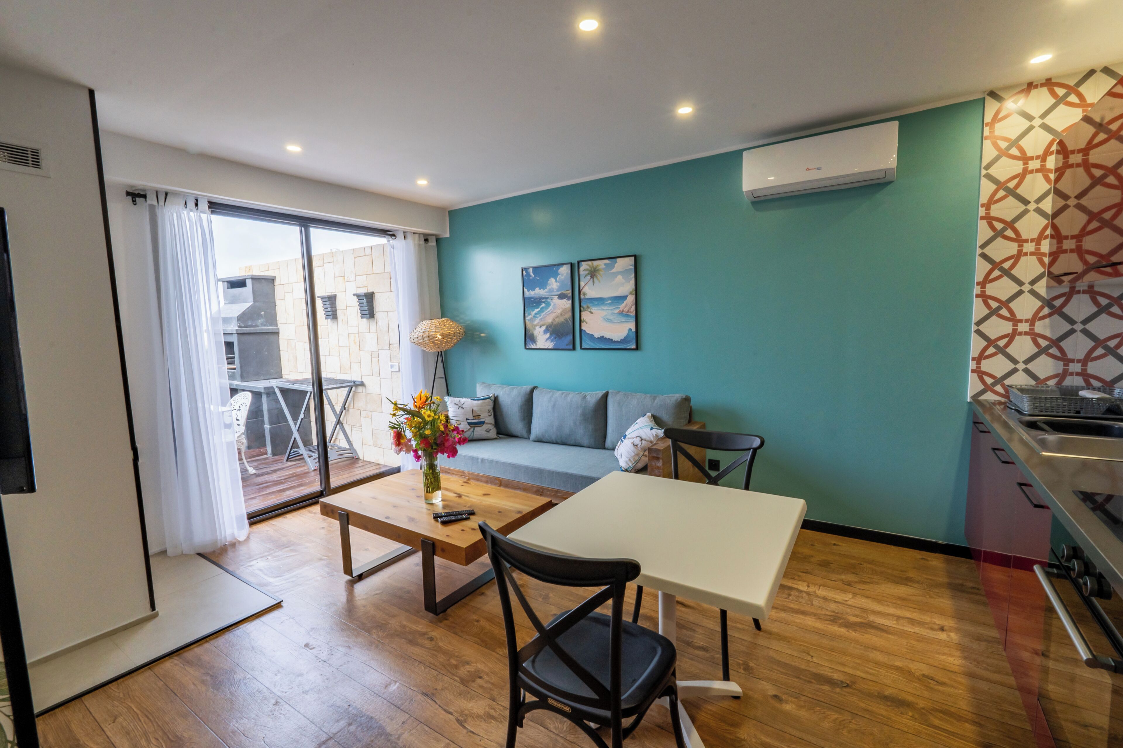 Un espacio habitable moderno con sofá, mesa de comedor, mesa de centro y zona de cocina.