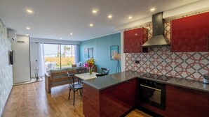 A modern kitchen with a central island, built-in oven, and red cabinetry.
