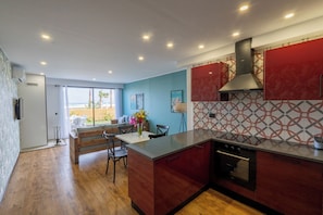 A modern kitchen with a central island, built-in oven, and red cabinetry. - Diar Yasmine  (Tazerka)