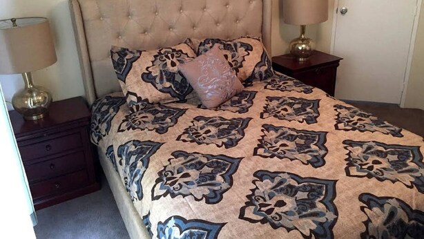 A bedroom with a tufted headboard, a patterned bedspread, two bedside lamps, and a nightstand. - Spacious Modular Rental on Huge Horse and Cattle Farm near Charlottesville, Virginia (Gordonsville)