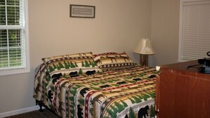 Un dormitorio con cama, escritorio, lámpara y una cita enmarcadas en la pared.