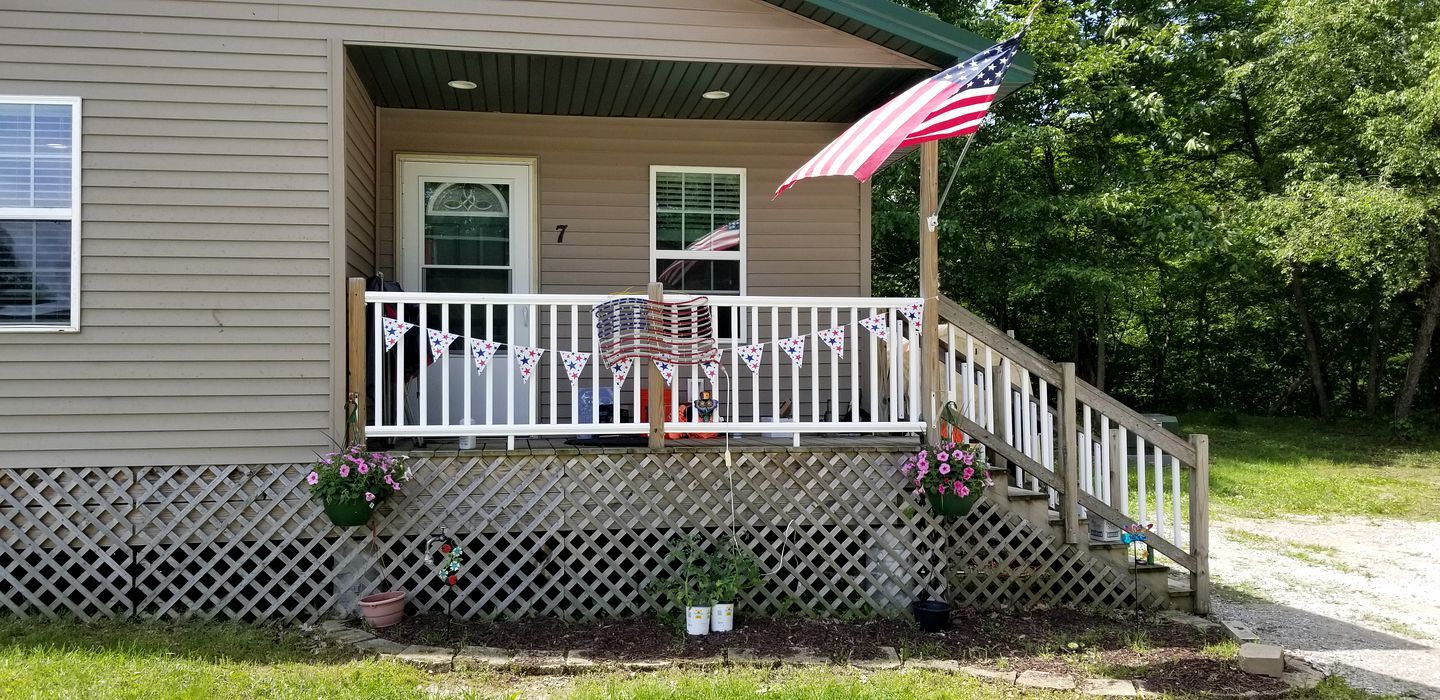 Une maison avec un porche, un drapeau et le chiffre « 7 » sur la porte.