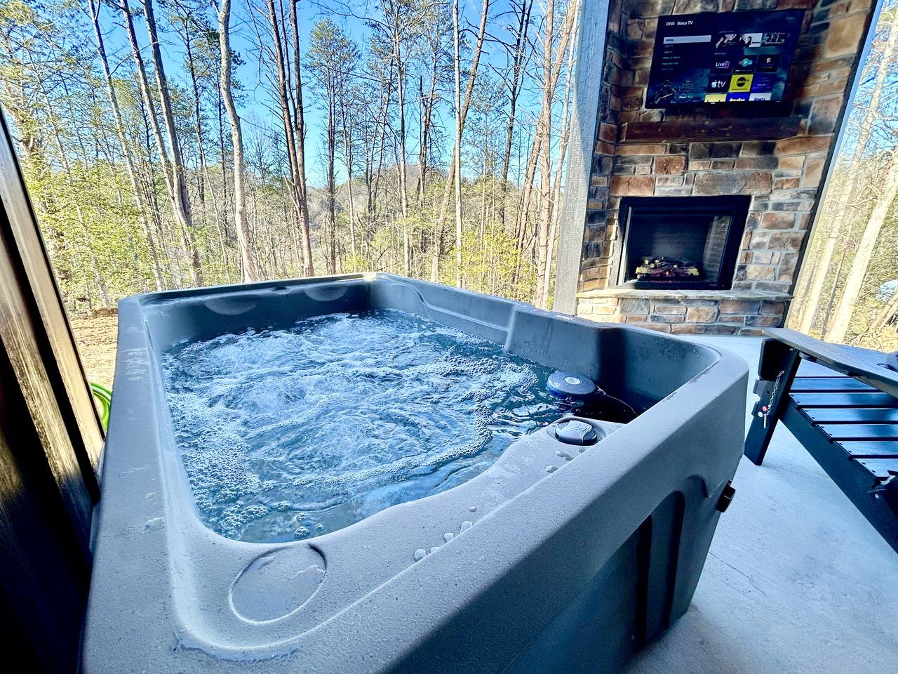A hot tub with a stone fireplace and a TV screen displaying channels.