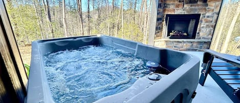 A hot tub with a stone fireplace and a TV screen displaying channels.