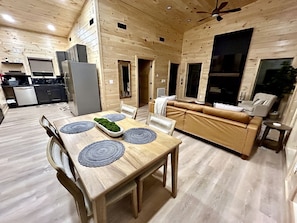 Ein Holzinnenraum mit Esstisch, Stühlen, einer Couch und einem Deckenventilator.
