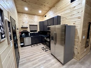 A wooden-paneled kitchen with a refrigerator, oven, and dark cabinets. - Romantic Cabin in Shady Grove Area of the Smoky Mountains: A Perfect One-Level Retreat for Couples (Sevierville)