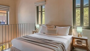 Un dormitorio con una cama, dos mesitas de noche, una lámpara y una ventana.