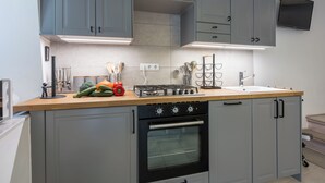 Eine moderne Küche mit grauen Schränken, einer Holz Arbeitsplatte, einem Gasherd und einem Backofen.