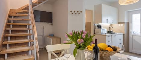 Una cocina moderna con armarios blancos, una mesa de comedor dispuesta con platos, cubiertos y un jarrón de flores.
