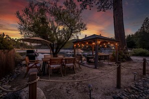 Un espacio al aire libre con una pérgola, sillas de madera y una parrilla.