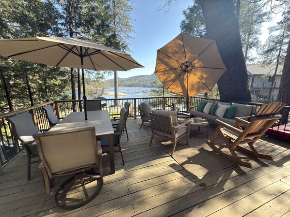 A wooden deck with outdoor furniture, including a table, chairs, and a sofa.
