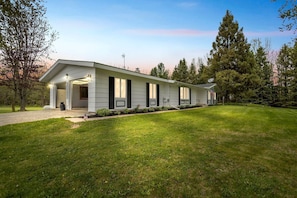 A modern single-story house with a covered porch, a well-maintained lawn, and a satellite dish.