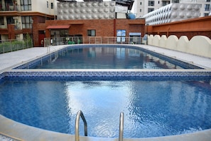A swimming pool with tiled edges, surrounded by a brick wall and a metal fence. - Sky homes 3bedroom with a park view (Syokimau)