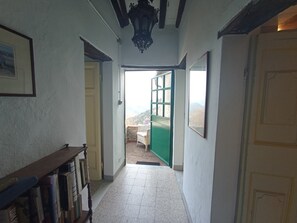 A hallway with a bookshelf, a green door leading outside, and a framed picture on the wall. - A charming retreat witha nice view and a garden with barbecue and Jacuzzi (Gombitelli)