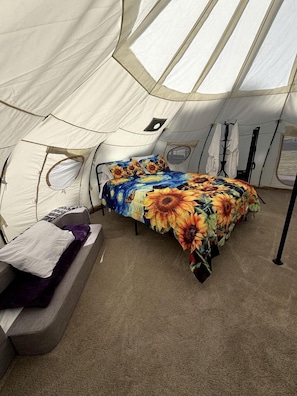 A tent with a bed, a bench, and a small table.