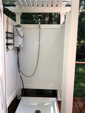 Alojamiento exterior para ducha con manguera, caja de control y desagüe.