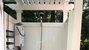 Alojamiento exterior para ducha con manguera, caja de control y desagüe.