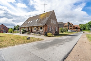 A two-story house with a sloped roof, a satellite dish, and a paved driveway. - Apartment Herian with Shared Garden on the Edge of Müritz National Park (Schloen-Dratow)