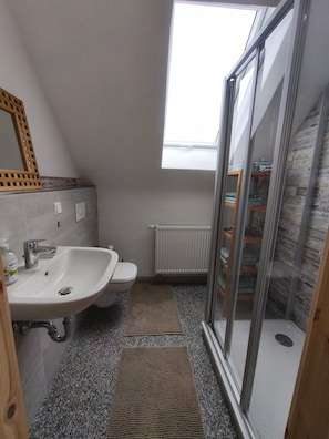 A compact bathroom with a sink, toilet, and a shower area.