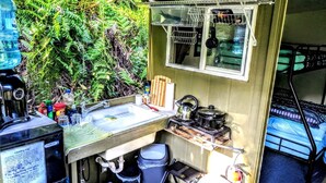 A compact kitchen with a sink, kettle, and storage shelves.