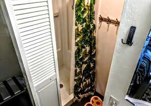 A bathroom with a shower curtain, a towel rack, and a door with a handle. - Rustic Vacation Rental Surrounded by Rainforest close to Volcanoes National Park, Hawaii (Pepeekeo)