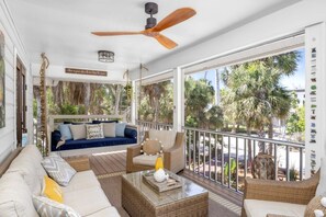 Un balcón amplio con ventilador de techo, mobiliario de mimbre y vistas a palmeras.
