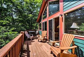 Eine Holzterrasse mit Stühlen und einem Tisch, umgeben von viel Grün.
