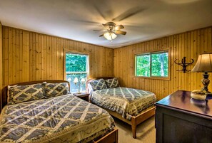 A room with two beds, a ceiling fan, a window with a view of trees, and a lamp on a table. - Spacious Vacation Cabin with a Fire Pit in Bryson City, North Carolina (Bryson City)