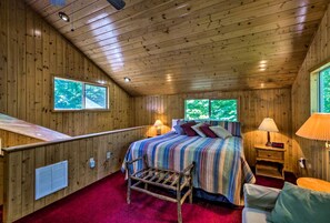 Ein Schlafzimmer einer Holzhütte mit einem Bett, zwei Fenstern, einem Heizkörper und einem Nachttisch.