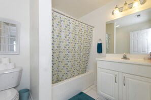 Un baño con inodoro, cortina de ducha, lavabo, espejo y una toalla azul.