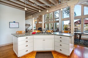 A modern kitchen with a granite countertop, white cabinetry, and a stone backsplash.
