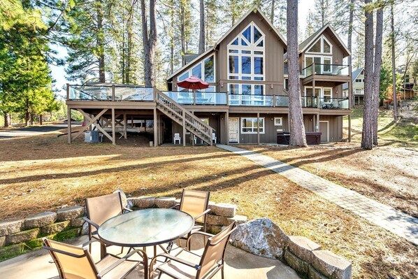 A two-story cabin with a deck, outdoor seating, and a staircase leading to the upper level.