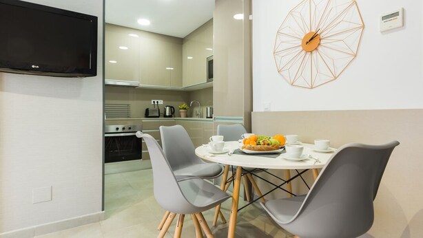 Una cocina moderna con comedor, un televisor de pantalla plana y un adorno geométrico en la pared.