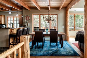 Un coin repas rustique avec une table en bois, des chaises et un lustre.