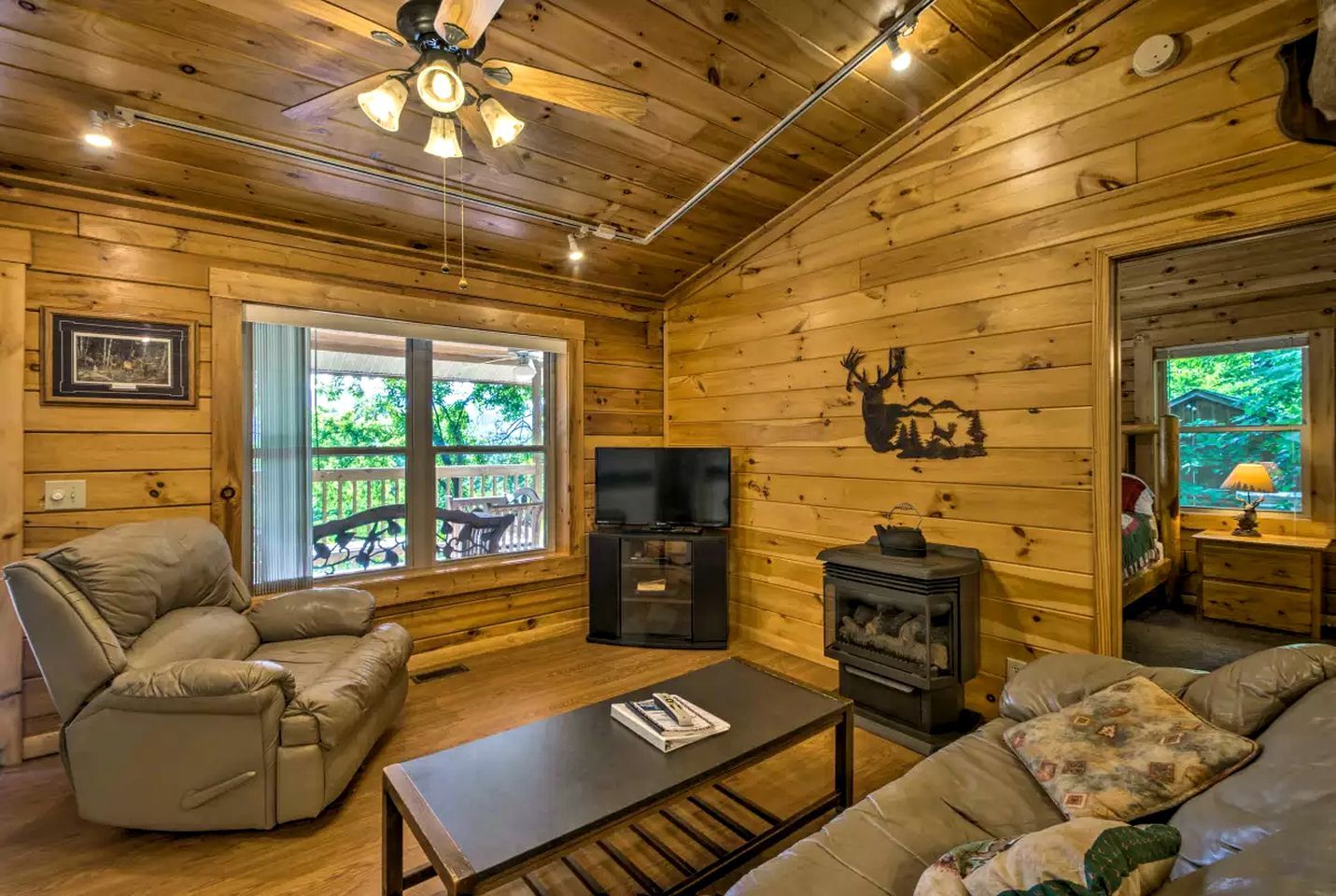 A log cabin interior with a fireplace, a television, a sofa, and a recliner.