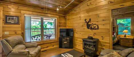 A log cabin interior with a fireplace, a television, a sofa, and a recliner.