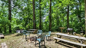 Un terrain de camping équipé de tables de pique-nique, de chaises, d’un foyer et d’un barbecue.