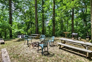 Ein Campingplatz mit Picknicktischen, Stühlen, einer Feuerstelle und einem Grill.