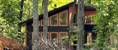 A modern cabin with large windows, surrounded by trees.