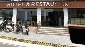 A hotel with a 'HOTEL & RESTAURANT' sign, multiple windows, and a few parked motorcycles. - HOTEL KAMAL RESIDENCY BY UK SEASON (Tehri)