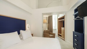 Une chambre d’hôtel avec un grand lit, une chaise, une armoire et un téléviseur.