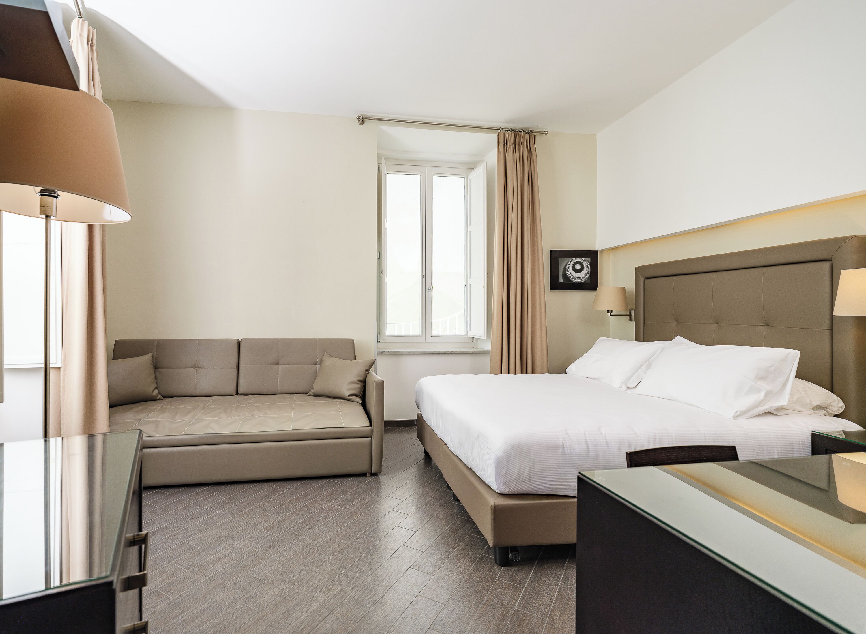 Une chambre d’hôtel avec un lit, un canapé, un bureau et une fenêtre.