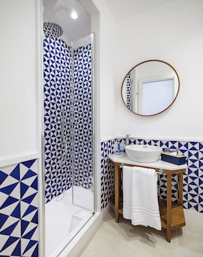 Une salle de bain avec une douche, un lavabo, un miroir et des carreaux décorés.