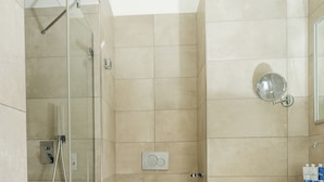 Une salle de bain moderne avec une douche à parois de verre, des toilettes blanches et un meuble-lavabo avec un miroir.